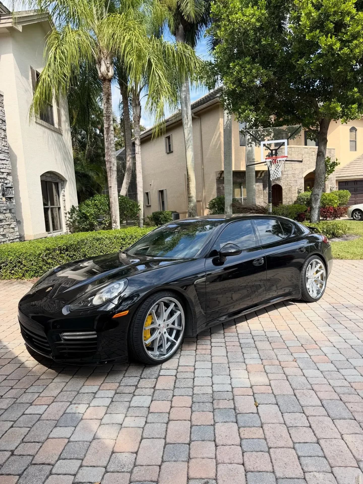 A black Porsche Panamera, freshly detailed on a paver driveway